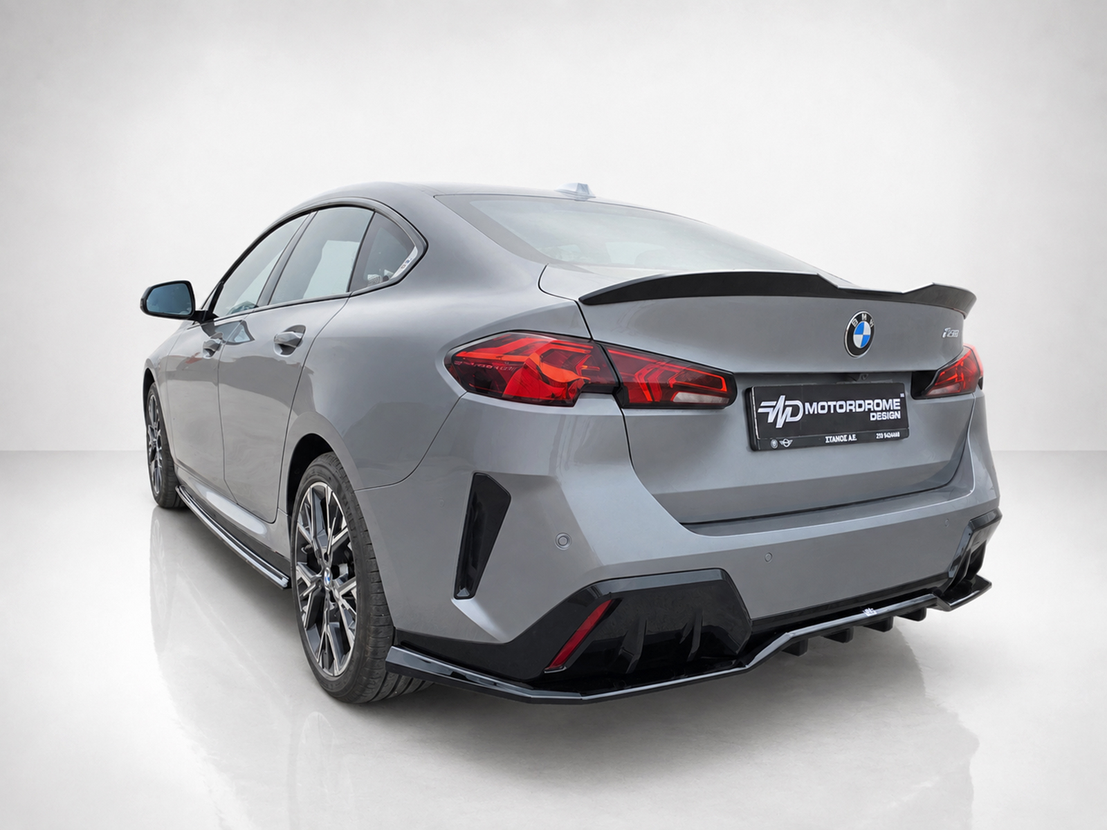 K215-008_2jpg - OPSHOLDERS Rear three-quarter view of a gray BMW with a large rear spoiler and aggressive diffuser in a studio setting
