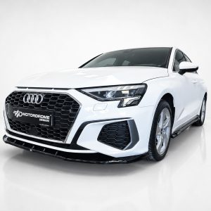 White Audi sedan in a studio, three-quarter front view showing the hexagonal grille and emblem