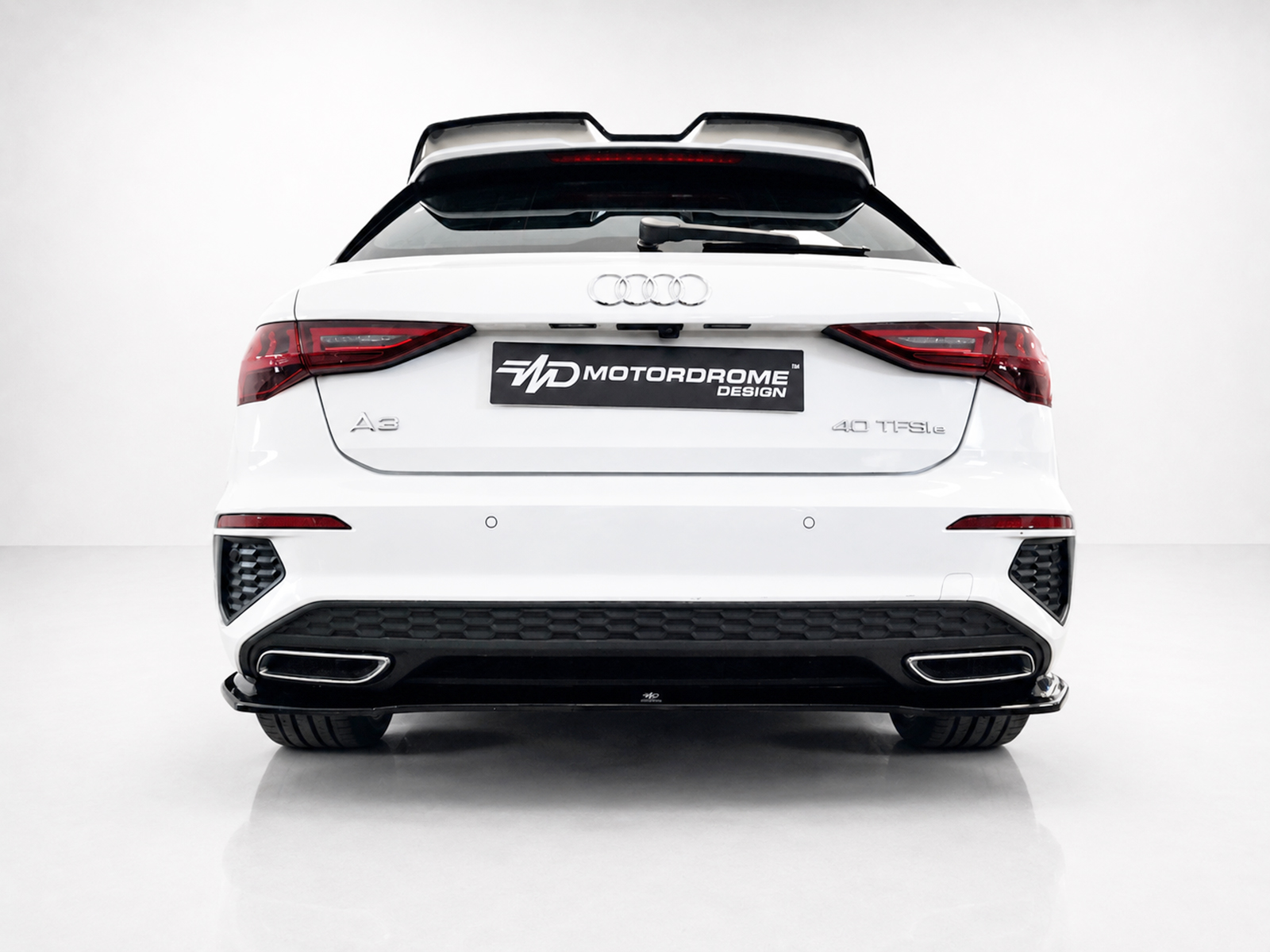 K216-003_1jpg - OPSHOLDERS Rear view of a white Audi A3 with a black MD Motorodrome Design plate, taillights lit, and a sporty rear bumper.