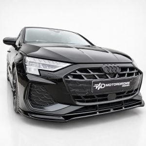 Black Audi at a three-quarter front view in a white studio, showing sleek grille and headlights with a Motordrome Design plate