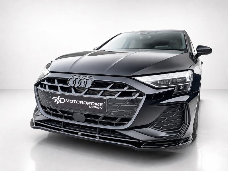 Front view of a dark gray Audi with a prominent grille and 'Motordome Design' plate in a studio setting
