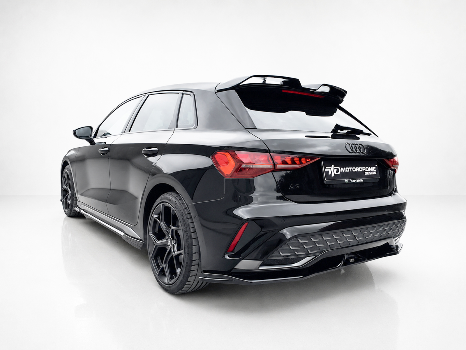 K216-005_2jpg - OPSHOLDERS Rear three-quarter view of a glossy black Audi SUV with a rear spoiler, red taillights, and large black wheels in a white studio setting.
