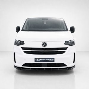 Front view of a white Volkswagen van in a bright studio, VW badge on the grille and a Motorodrome plate.