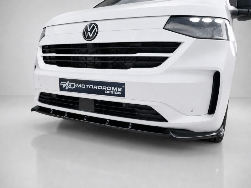 Front view of a white Volkswagen van with a custom splitter and black grille, displaying a Motordrome Design plate plate on the bumper.