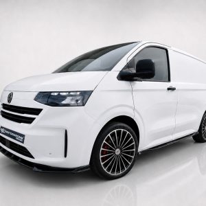 Three-quarter front view of a white modern van with black grille, large alloy wheels, and a clean glossy finish in a studio setting.