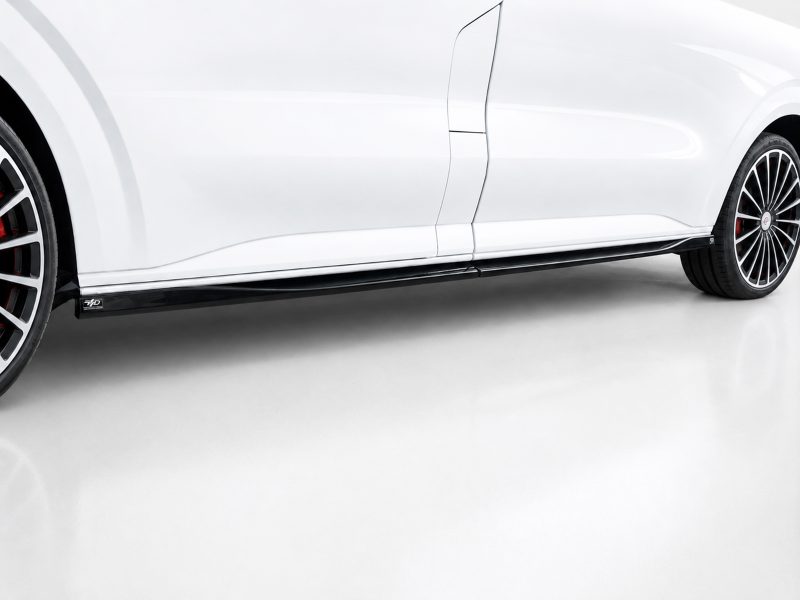 K217-004_3jpg - OPSHOLDERS Side view of a white sports car showing the black lower side skirt and stylish multi-spoke wheels with red brake calipers in view.