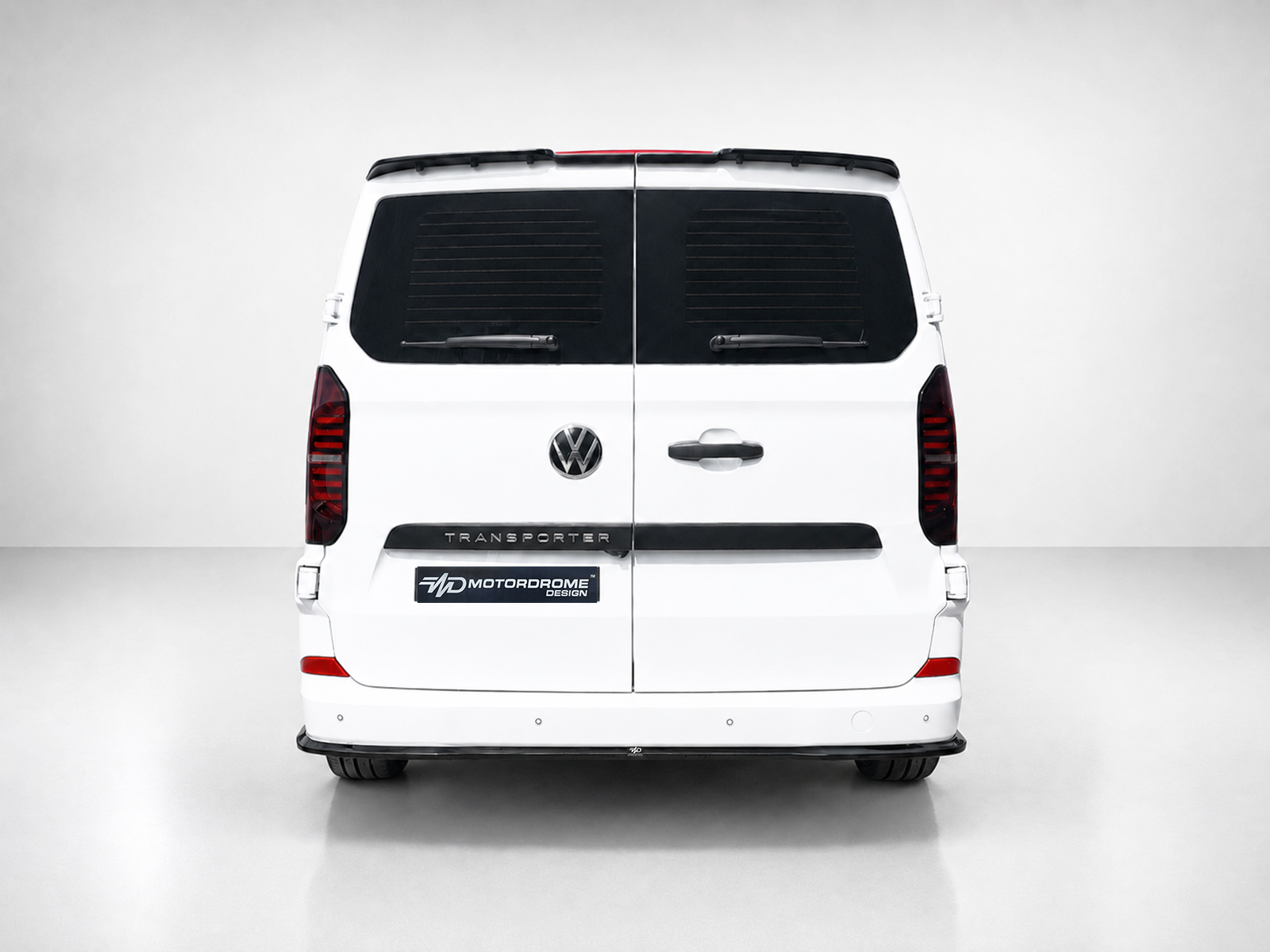 K217-006_2jpg - OPSHOLDERS Rear view of a white Volkswagen Transporter van with split rear doors, VW emblem, dark rear windows, and a Motordome Design plate on the bumper area.