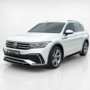 K218-001_4jpg - OPSHOLDERS Front three-quarter view of a white Volkswagen SUV in a studio setting with a chrome grille and alloy wheels.