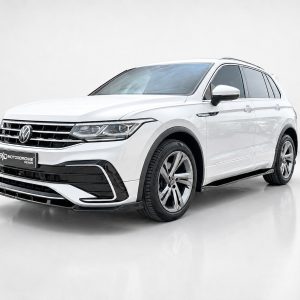 White VW SUV with a bold front grille, parked indoors on a glossy floor, angled three-quarter view