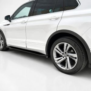 White SUV side view focusing on the wheel, tire, and lower body panel in a bright studio setting.