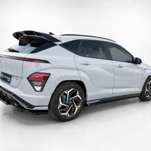Rear three-quarter view of a silver luxury SUV with a large rear spoiler and dark glass panels, shown against a neutral backdrop.