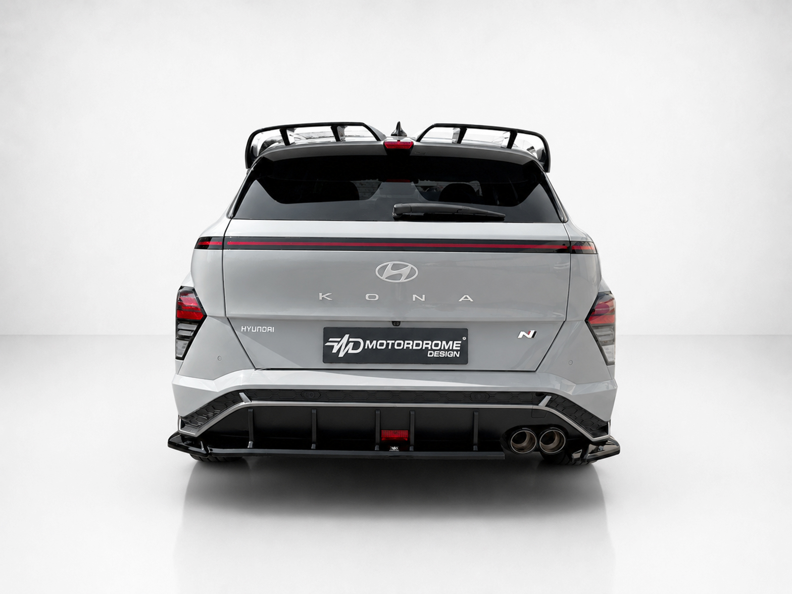 K219-003_1jpg - OPSHOLDERS Rear view of a silver Hyundai Kona N with a custom Motordrome Design plate, dual exhausts, and a roof rack edge detail.