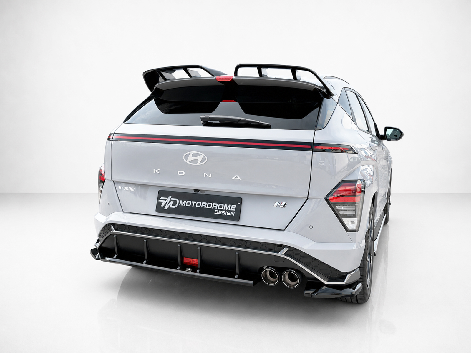 K219-003_2jpg - OPSHOLDERS Rear view of a silver Hyundai Kona N with a large rear spoiler and Motordrome Design body kit in a studio setting.