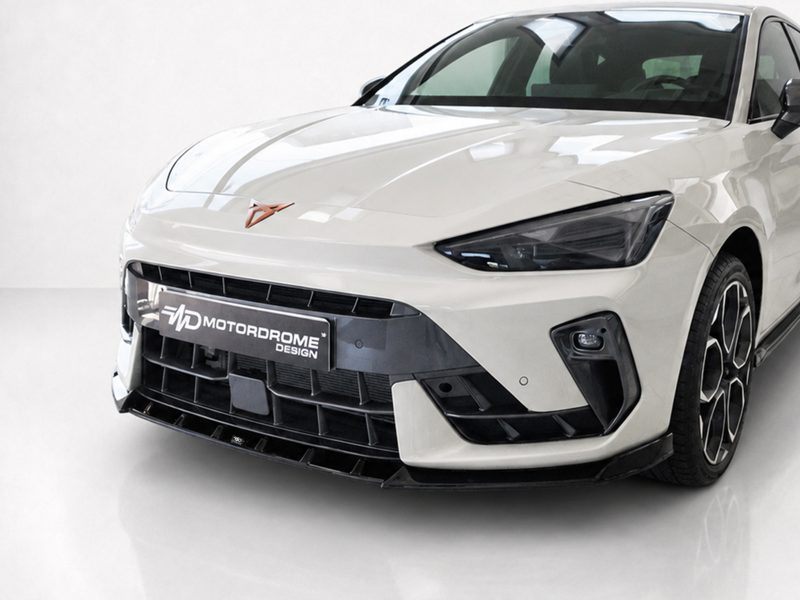 Front view of a white sports car with a bold black grille and angular headlights, license plate reading 'Motordrome Design'