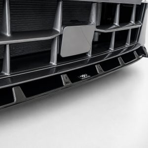 Close-up of a glossy black car front grille with chrome vertical bars and a central rectangular emblem, photographed from a low angle.
