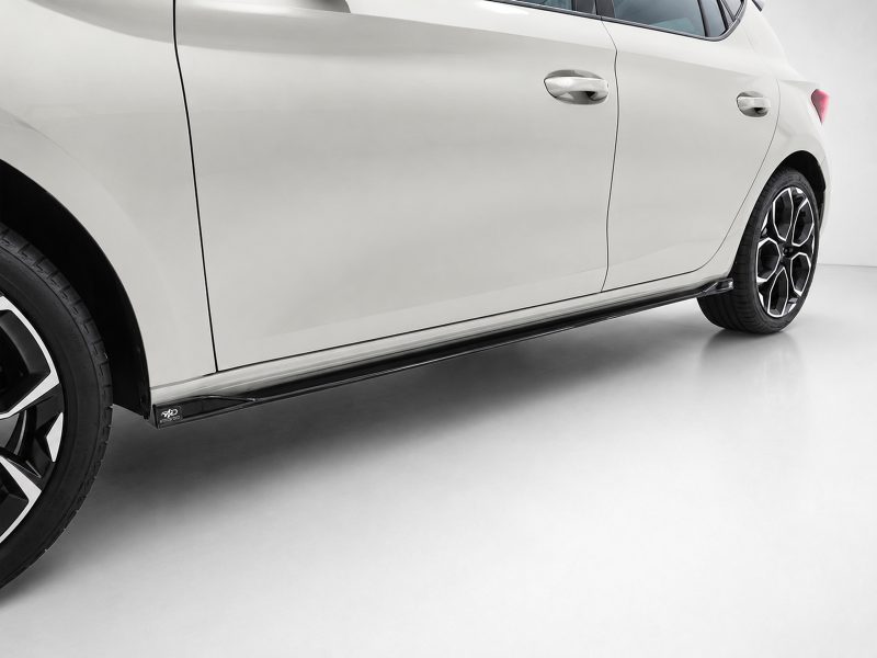 White car side view showing doors, handles, and a black side skirt with alloy wheels on the rear half of the car.