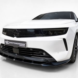 Front angle view of a white sports car with a glossy black grille and slim headlights; Motordrome Design license plate visible on the bumper.