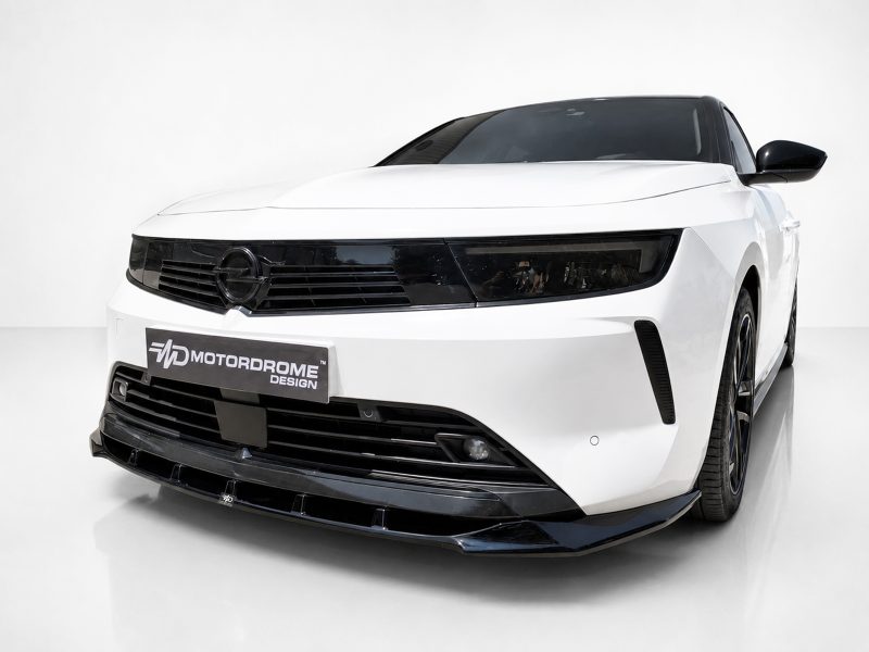 Front angle view of a white sports car with a glossy black grille and slim headlights; Motordrome Design license plate visible on the bumper.