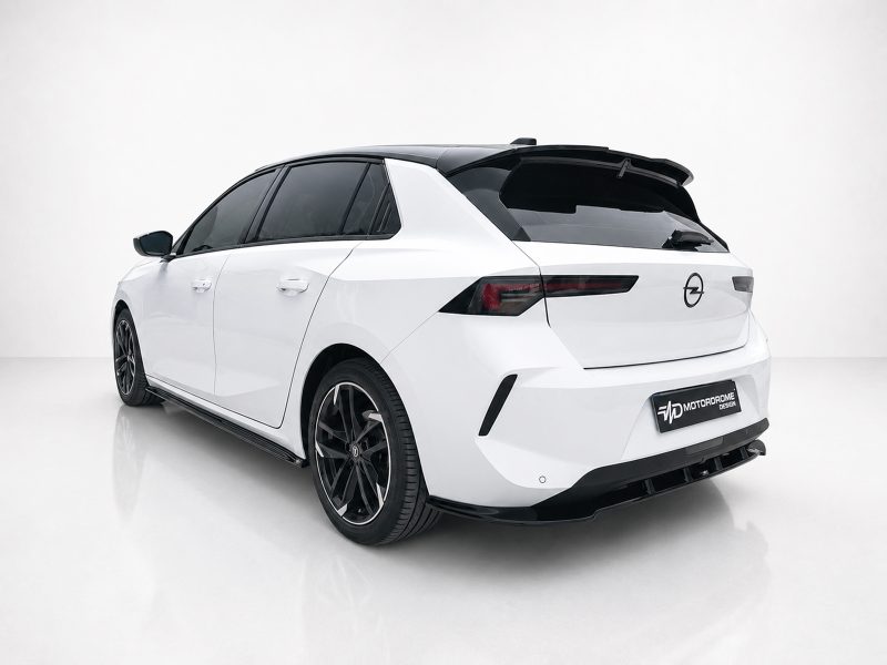 Rear-left three-quarter view of a white hatchback with a black roof spoiler in a bright studio. Dark tinted windows and large black alloy wheels visible.