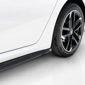 Close-up of a white car's rear wheel and glossy black alloy rim, with a low side skirt visible beneath the door panel.