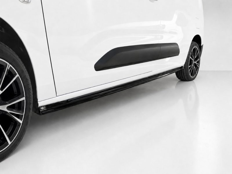 K222-002_3jpg - OPSHOLDERS Close-up of a white car's side showing the black running board and rear wheel on a glossy floor