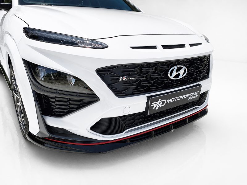 Front angle of a white Hyundai with black honeycomb grille, N Line badge, and sporty lower splitter with red accents.