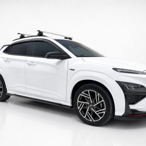 White SUV with roof rack on a clean studio backdrop; angled side view showing sporty wheels and black accents.