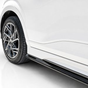 Close-up of a white car's alloy wheel and lower body panel in a studio setting.