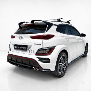 Rear three-quarter view of a white Hyundai Kona with a black diffuser, dual exhausts, and roof rack accessories in a studio setting.