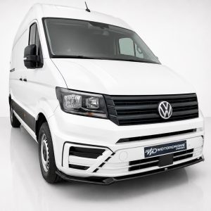 Front-left view of a white VW cargo van showing the grille and headlights in a studio setting, logo visible at center.