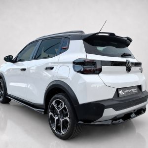 White compact SUV shown from a rear three-quarter angle, with black roof, alloy wheels, and Motorodrome Design badge in a studio setting.