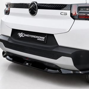 Rear view of a white SUV showing the black rear bumper, taillights, and a prominent Motordrome Design plate centered on the bumper.