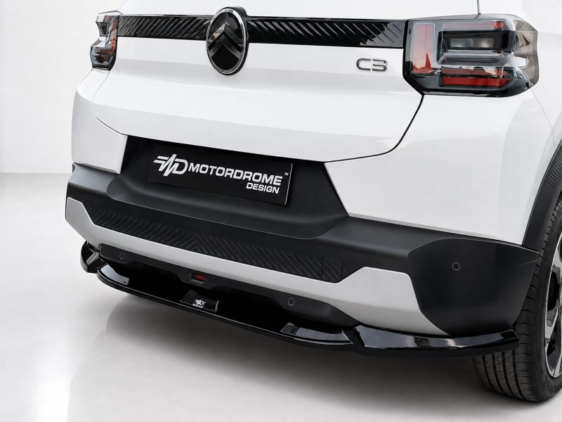 Rear view of a white SUV showing the black rear bumper, taillights, and a prominent Motordrome Design plate centered on the bumper.