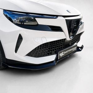 Close-up of a white modern car front, showing a black mesh grille, angular headlight with blue accents, and a front splitter.