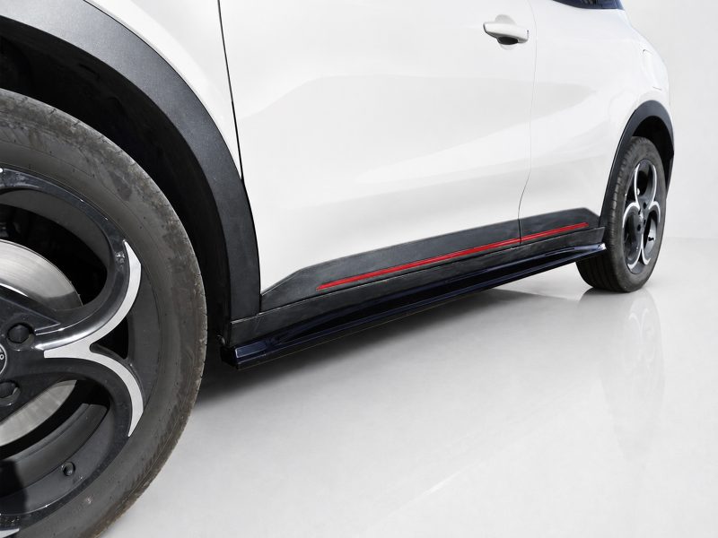 Close-up side view of a white car showing the front wheel, black fender, and red-accented side skirt along the lower body surface