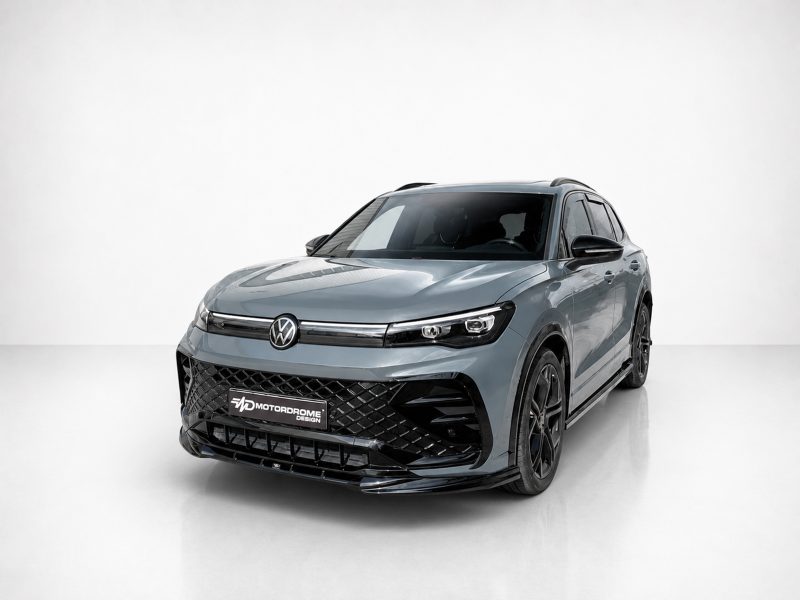 K228-001_3jpg - OPSHOLDERS Front three-quarter view of a blue-gray Volkswagen SUV in a white studio, highlighting the bold black grille and VW emblem.