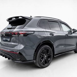 Rear three-quarter view of a dark gray Volkswagen Tiguan with black wheels in a bright studio setting