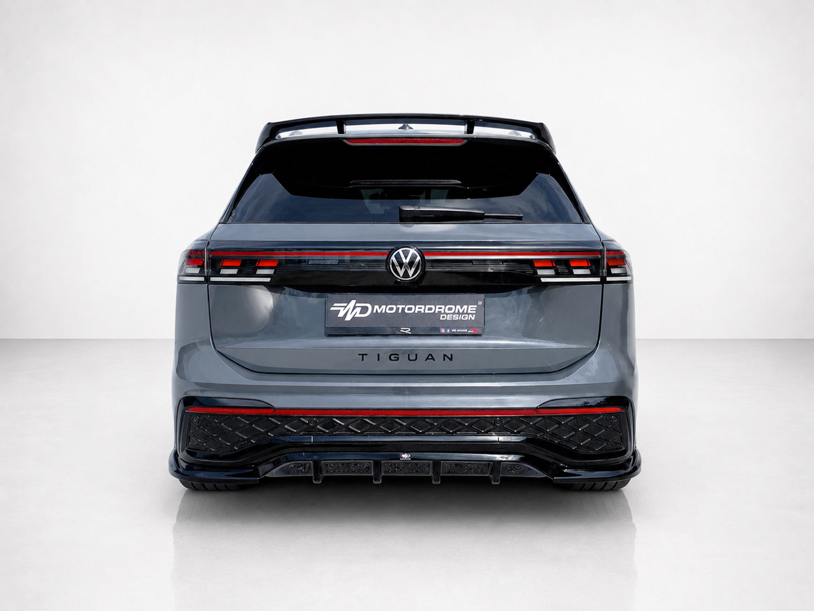 K228-004_2jpg - OPSHOLDERS Rear view of a gray Volkswagen Tiguan SUV with a Motordrome Design plate and red taillights