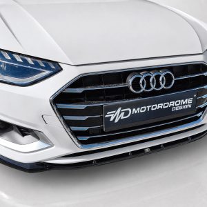Front view of a white Audi with a chrome-trimmed grille and four-ring emblem on glossy black bars.
