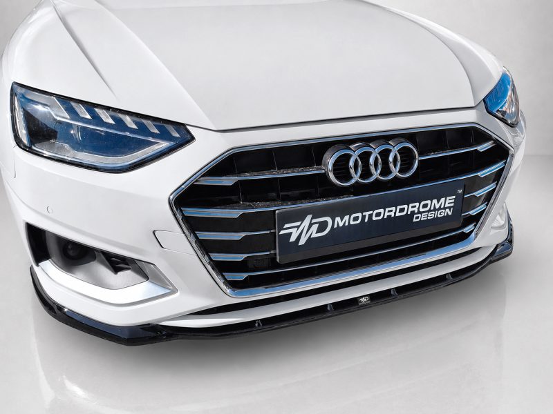 Front view of a white Audi with a chrome-trimmed grille and four-ring emblem on glossy black bars.