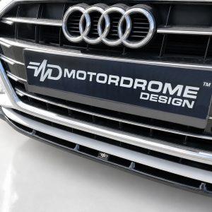 Front view of an Audi with the four-ring emblem and a black plate reading MOTORDROME DESIGN.