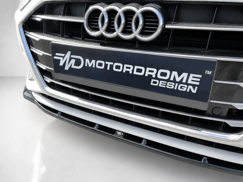 Front view of an Audi with the four-ring emblem and a black plate reading MOTORDROME DESIGN.