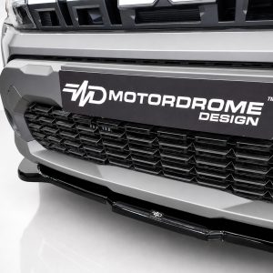 Close-up of a silver truck front with a black plate reading 'MD MOTORDOME DESIGN' over a segmented grille.