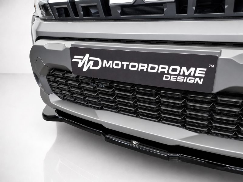 Close-up of a silver truck front with a black plate reading 'MD MOTORDOME DESIGN' over a segmented grille.