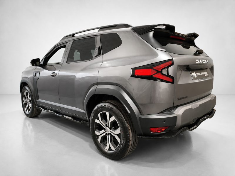 Silver Dacia Duster SUV shown from the rear three-quarter angle in a studio setting, highlighting the taillights, rear bumper, and roof rails