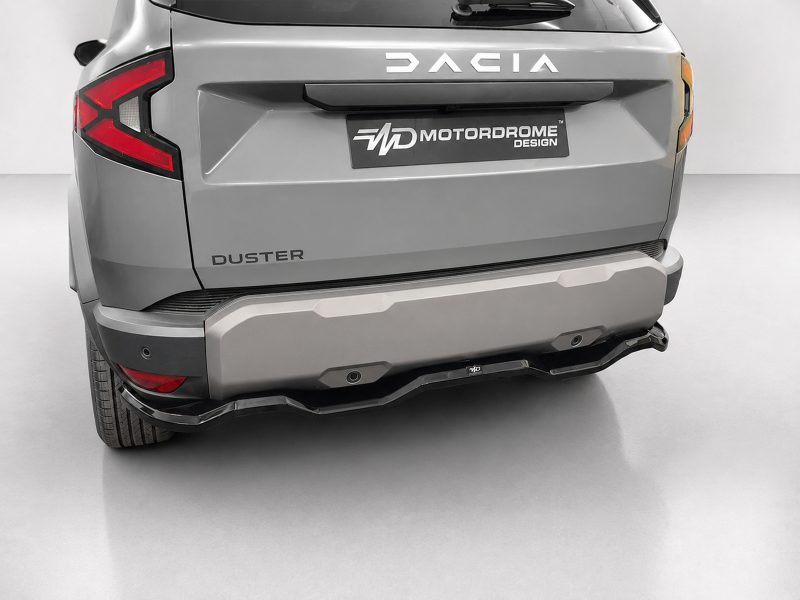 Rear view of a gray Dacia Duster with a Motordrome Design plate on the tailgate and distinctive taillights visible on the left.] ,