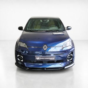 Front view of a blue Renault car in a white studio, showing the diamond logo, headlights, and a Motordrome Design plate.