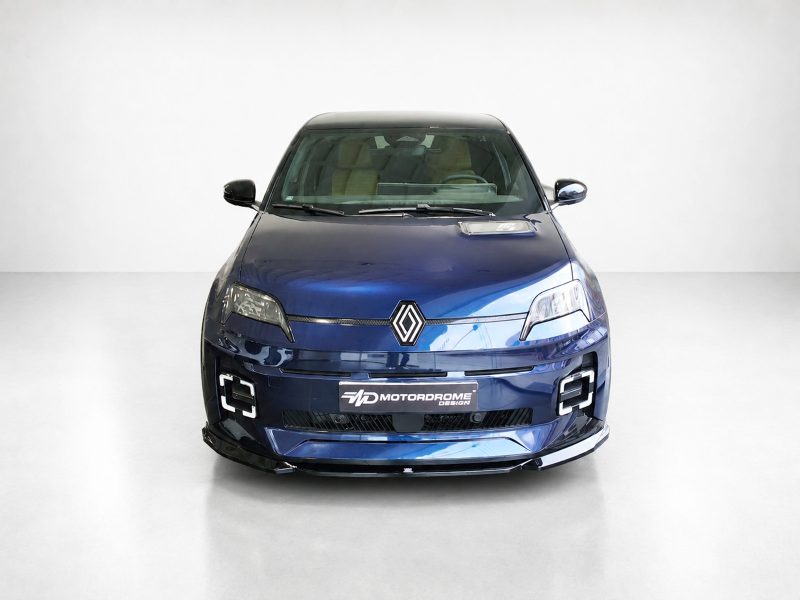 Front view of a blue Renault car in a white studio, showing the diamond logo, headlights, and a Motordrome Design plate.