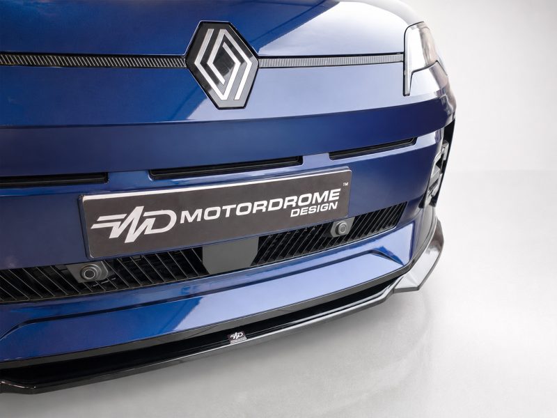 Close-up of a blue car's front end showing the Renault-style diamond badge and a 'Motordrome Design' license plate