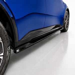 Close-up of a blue sports car's side panel, black side skirt, and alloy wheel visible at ground level.